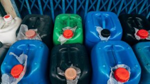 Galões de produtos químicos sem rótulo, com tampas coloridas, armazenados lado a lado