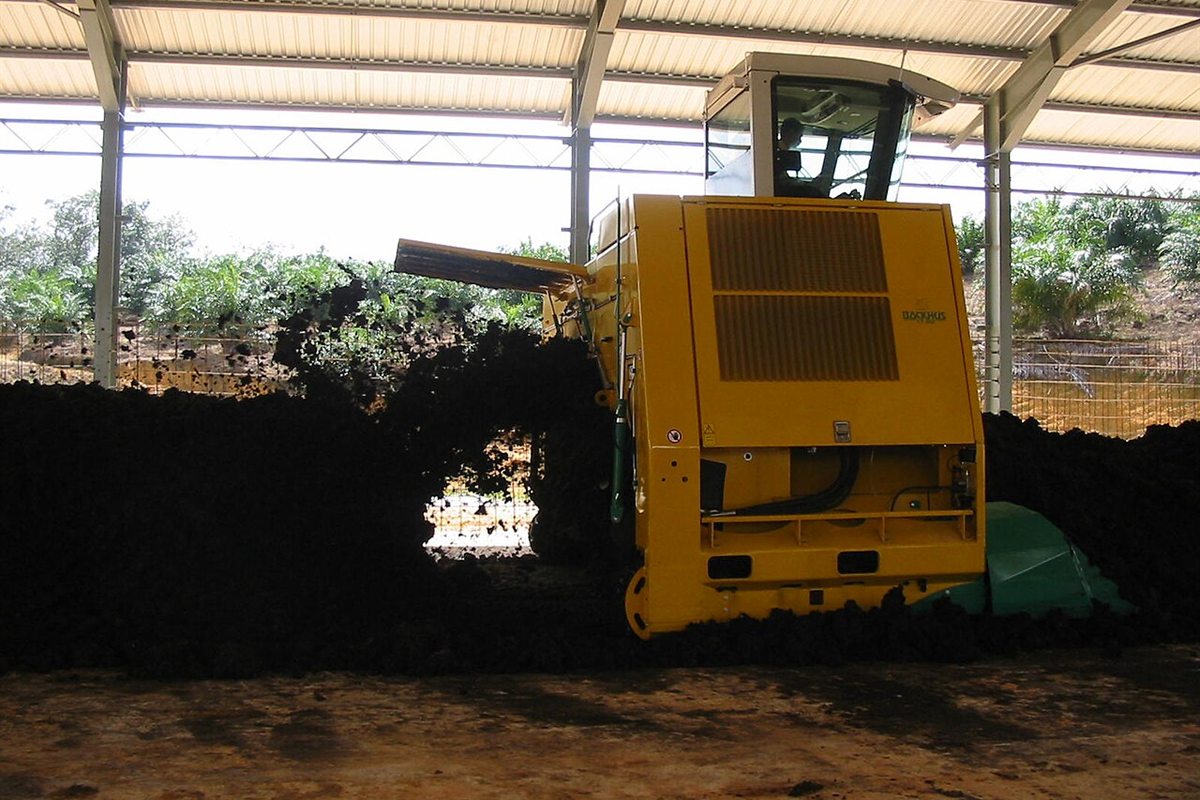 Revolvedora de leiras trabalhando em um pátio coberto de compostagem.