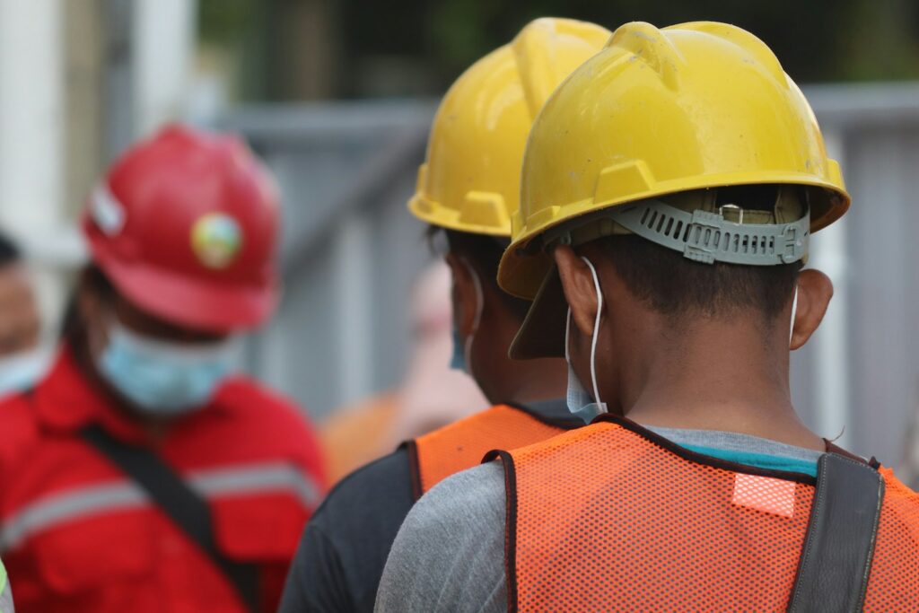 Trabalhadores com capacete e colete de segurança em área de trabalho
