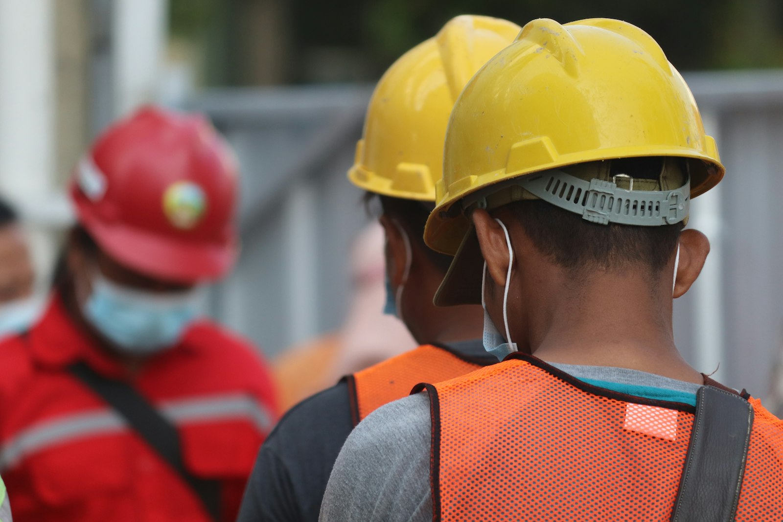 Trabalhadores com capacete e colete de segurança em área de trabalho